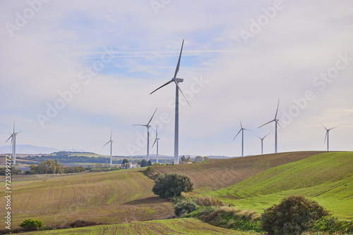 Wind turbines with landscape of agricultural fields under blue sky. Green energy concept.
