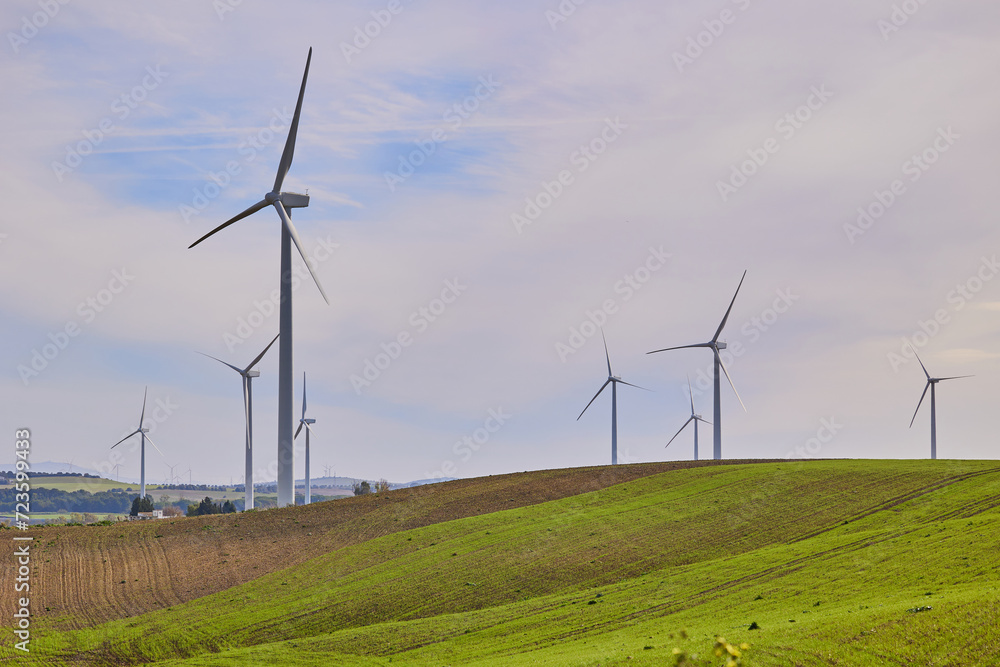 Wind turbines with landscape of agricultural fields under blue sky. Green energy concept.
