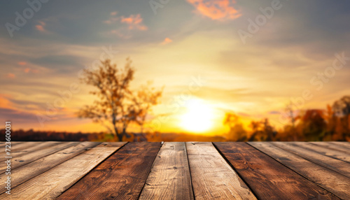 Wood table in autumn landscape with empty copy space for product display. and a golden sunset sky