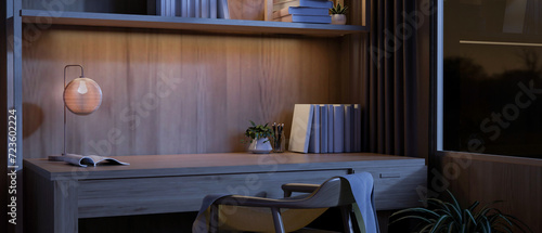 Foto A comfortable home working room at night with a wooden desk, books, and a dim light from a lamp
