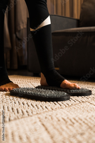 A woman in sportswear stands on the nails of a Sadhu at home. The concept of nailing practice. Spiritual development