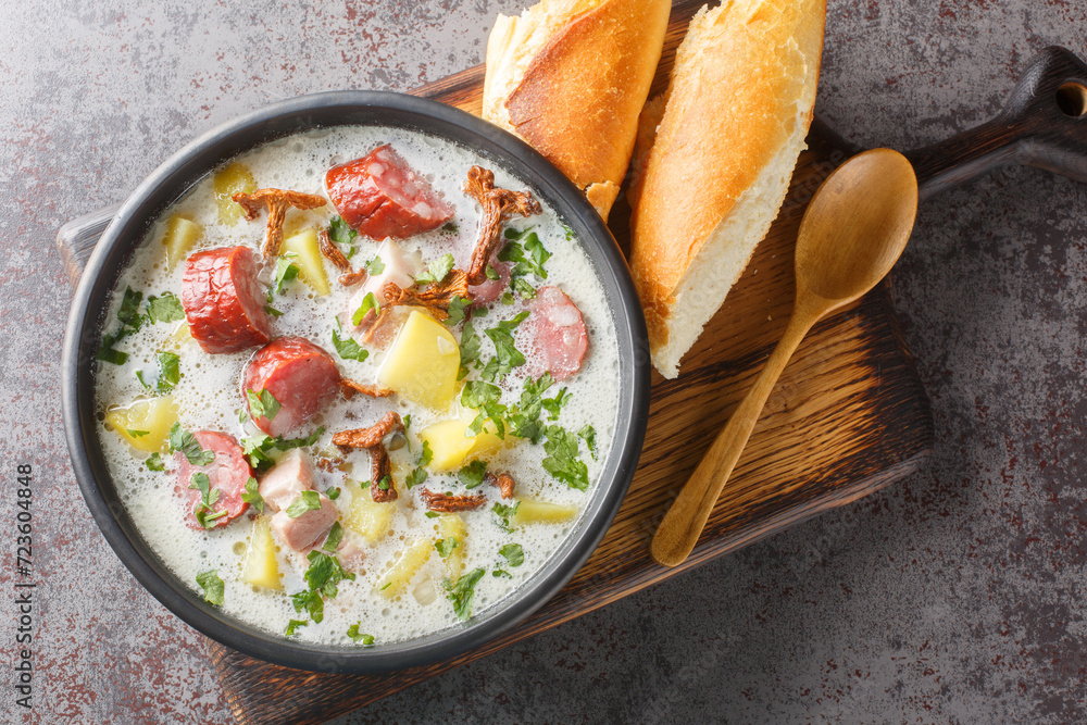 Zalewajka is a delicious traditional Polish sour rye soup with vegetables, sausage and dried mushrooms closeup on the plate on the table. Horizontal top view from above