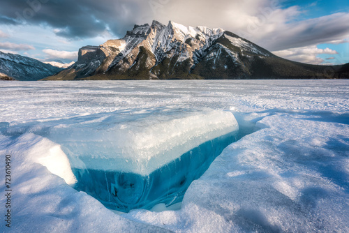 Frozen Lake Minnewanka with rocky mountains and cracked ice from the lake in winter at Banff national park