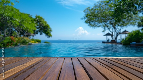 A smooth teak table surface set against the backdrop of a tropical pool and ocean view