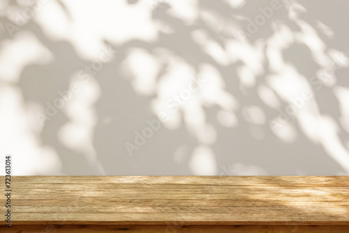 Fotografie Empty wood table top on beige wall texture with tree leaves shadow background