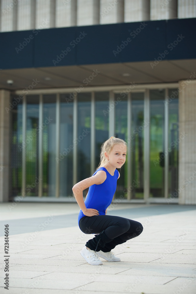 Girl gymnast school age in a suit shows the elements of the sport. Girl gymnast school age in a suit shows the elements of the sport.