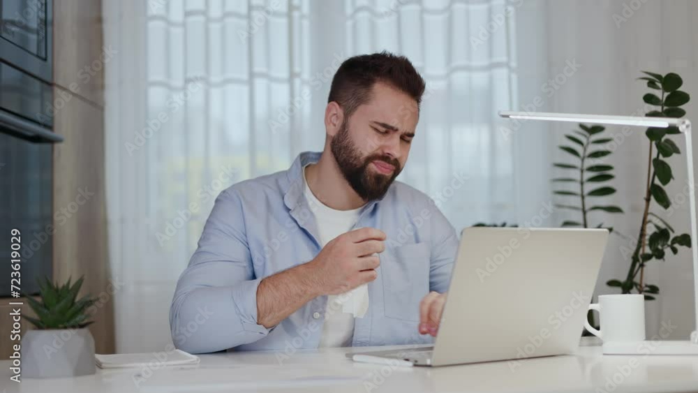 Sick male coughing into paper napkin while wincing from pain in lungs and keeping typing on laptop at home. Team leader with flu in stylish outfit refusing day off for finishing project in time. Sick male coughing into paper napkin while wincing from pain in lungs and keeping typing on laptop at home. Team leader with flu in stylish outfit refusing day off for finishing project in time.