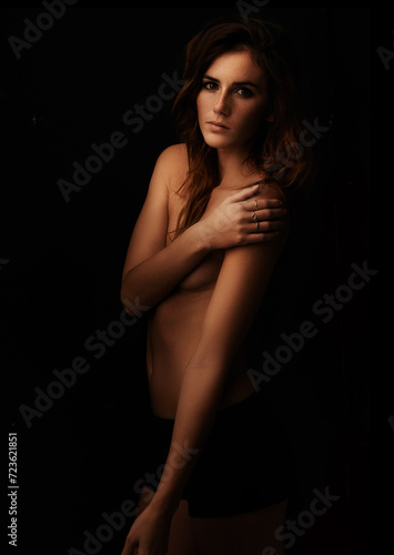 Woman, body and skincare in studio for beauty, dermatology and self care with luxury and art aesthetic. Portrait of a young model or serious person in shadow for cosmetics on a dark, black background