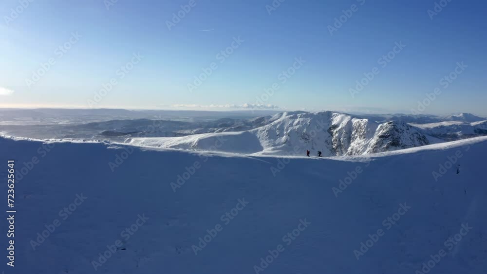 Couple walking a snowy peak of a great valley in the sunshine. Aerial dolly out Couple walking a snowy peak of a great valley in the sunshine. Aerial dolly out