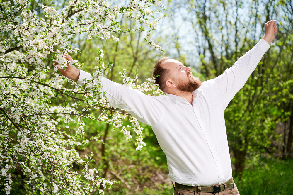 Man allergic enjoying after treatment from seasonal allergy at spring. Portrait of happy bearded man smiling in front of blossom tree at springtime. Spring allergy concept. Man allergic enjoying after treatment from seasonal allergy at spring. Portrait of happy bearded man smiling in front of blossom tree at springtime. Spring allergy concept.