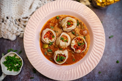 Momo dumplings in a white plate with spicy sauce Wooden background. delicious momos with chutney top view.