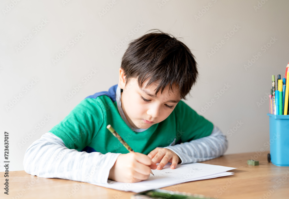 Education concept,School kid using black colour pen drawing or sketching on paper,Portrait boy siting on table doing homework in living room,Child enjoy art and craft activity at home Education concept,School kid using black colour pen drawing or sketching on paper,Portrait boy siting on table doing homework in living room,Child enjoy art and craft activity at home