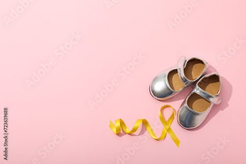 Silver children's shoes with a yellow ribbon