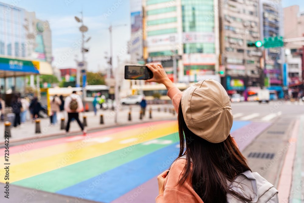 Obraz premium Young female tourist taking a photo of the Rainbow Road crossing at ximending in Taipei, Taiwan