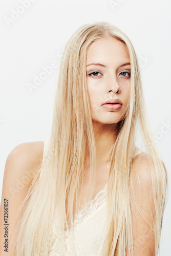 Portrait, woman and confident for cosmetics in studio, beauty and dermatology for glow of skincare. Young model, face and pride in make up with fashion lingerie and blonde hair by white background