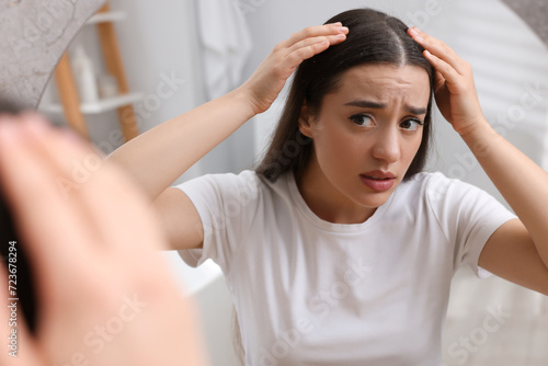 Emotional woman examining her hair and scalp at home. Dandruff problem photo