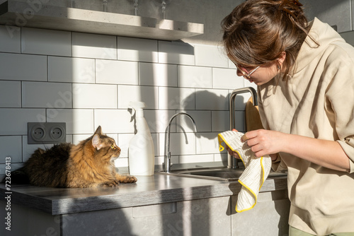 A young woman kills the kitchen with her pet cat. Cleaning an apartment with pets