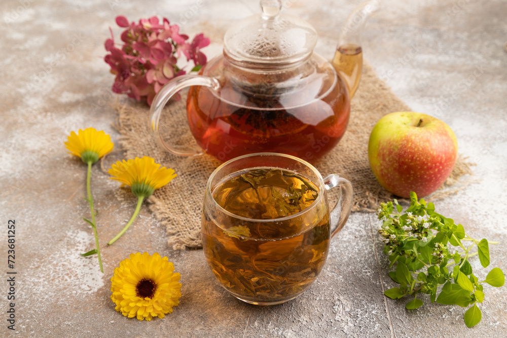 Red tea with herbs in glass teapot on brown concrete. Side view. Red tea with herbs in glass teapot on brown concrete. Side view.