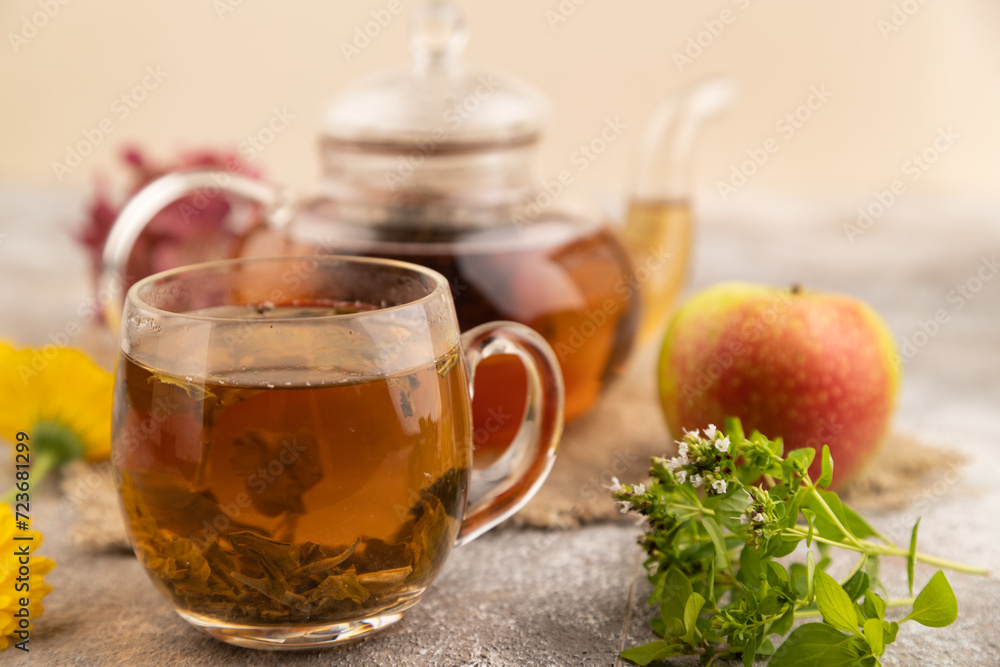 Red tea with herbs in glass teapot on brown concrete. Side view, selective focus. Red tea with herbs in glass teapot on brown concrete. Side view, selective focus.