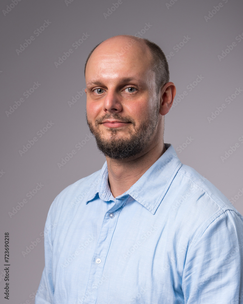 Fototapeta premium Portrait of a 35-year-old man with a beard in a blue shirt. Close-up
