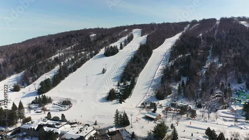 Drone video coming down slowly showing the skiiers on the sky slopes in the Laurentians enjoying a beautiful sunny day of winter
