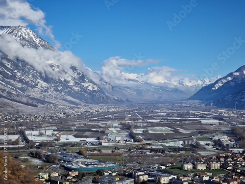 A small town surrounded by snow-covered mountains and farm fields during the winter season
