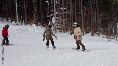 snowboarder on a snowboard teaches a girl to ride at a ski resort in the mountains, adrenaline and pleasure from winter sport and tourism