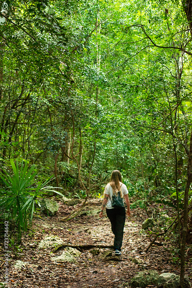 hiker on a path through the dense, shady tropical jungle of the Yucatan