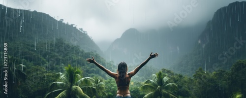 happy woman embracing the warm tropical rain as she swims in an infinity pool, overlooking the lush jungle. photo