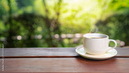 A Cup of coffee on wooden table with nature background. morning time in the garden