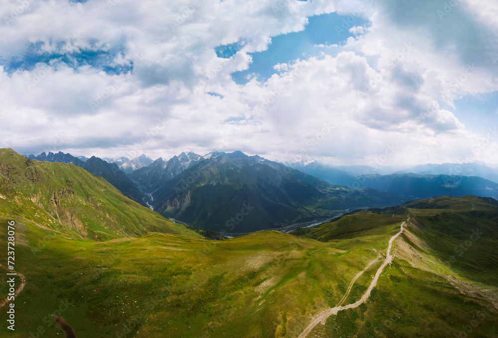 Aerial view at the Koruldi lakes. Green hills, high mountain pastures. Summer day. in the background are the snowy peaks of the Caucasus Mountains. High resolution panorama