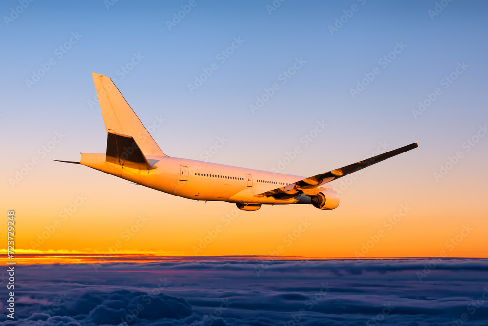 Naklejka premium White wide body passenger jetliner fly in the sunset sky