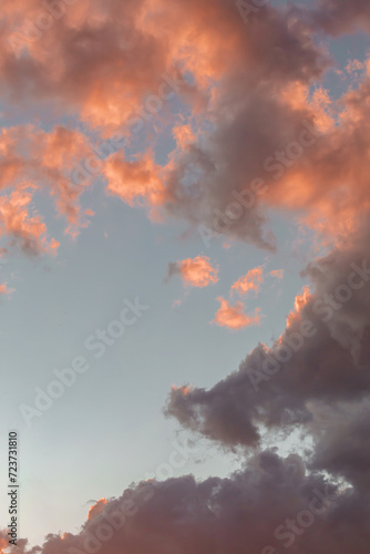 Dramatic cumulus clouds on sunny day at sunset painted in purple with sun. Atmosphere multicolor vertical background or wallpaper