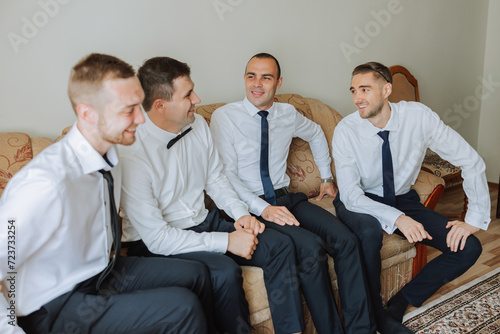 stylish groom laughing and having fun with groomsmen while getting ready in the morning for wedding ceremony. luxury man