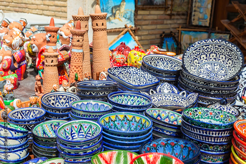 Ornamented ceramic bowls and models of Islam-Khodja (Islomxo'ja) minaret. Typical handmade Khiva's souvenires. Close-up, selected focus. Khiva (Xiva), Uzbekistan. April 10, 2023 photo
