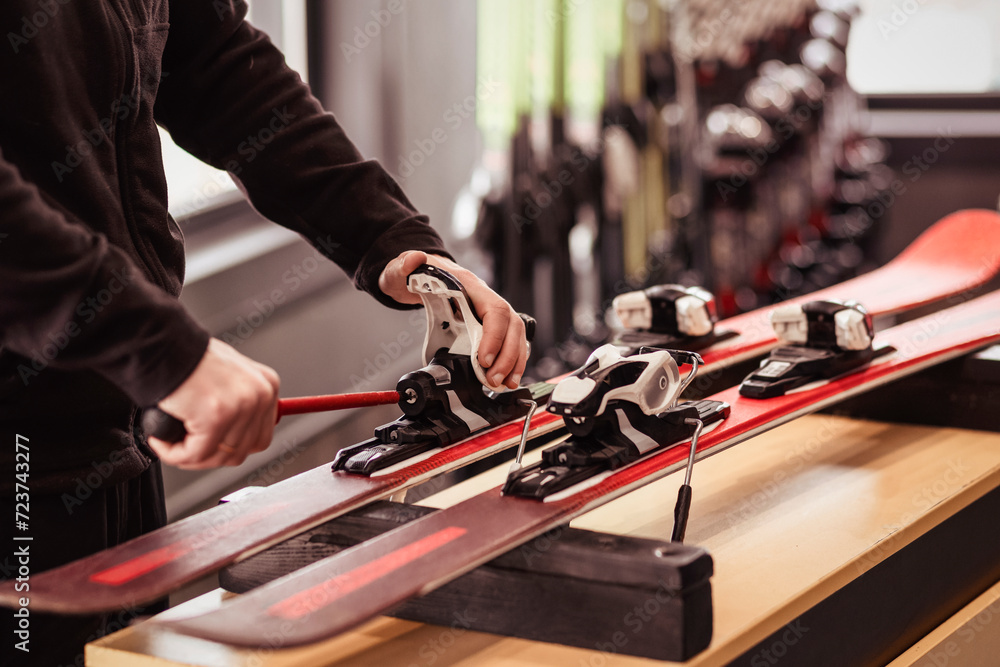 Skis for Rent. Ski Rental Service. Ski Repair Shop Worker Adjust the Bindings and Equipment with Screwdriver. Ski Workshop Service. - obrazy, fototapety, plakaty 
