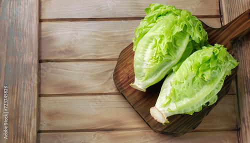 Iceberg lettuce on cutting board on wooden table background, top view. Two whole heads of fresh crisphead lettuce. Leafy green vegetable, selective focus