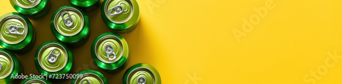 Background with copy space and a collection of green aluminum cans on a bright yellow backdrop, underscoring the recyclability of metal and the push for beverage container recycling. photo