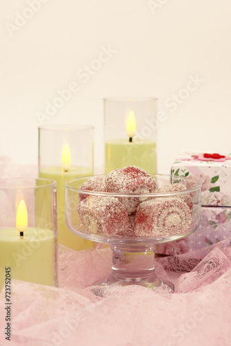Candles, dessert and gift boxes on delicate pink fabric. Poster for interior. Romantic mood in the form of candles and gifts.