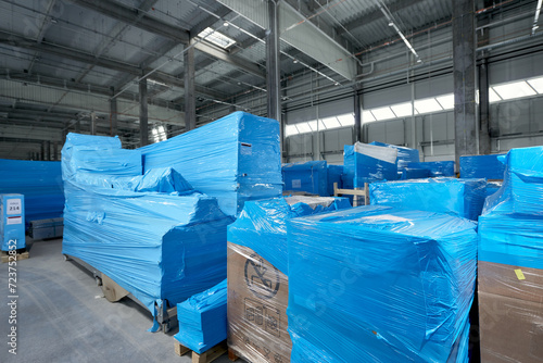 Products and boxes are stored in a warehouse, wrapped in blue stretch film photo