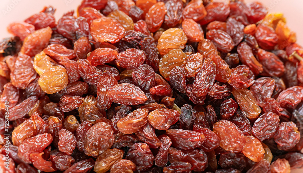 Raisins texture background, closeup, top view. Heap of dried red grapes, selective focus photo; blurred foreground and backdrop Raisins texture background, closeup, top view. Heap of dried red grapes, selective focus photo; blurred foreground and backdrop