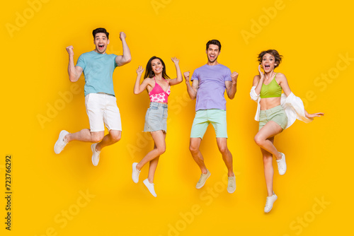 Full body photo of cheerful people buddies jump with raised fists winning isolated over bright color background photo