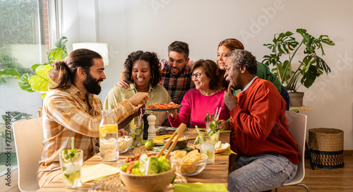 group of multicultural friends sharing a pizza at weekend meal
