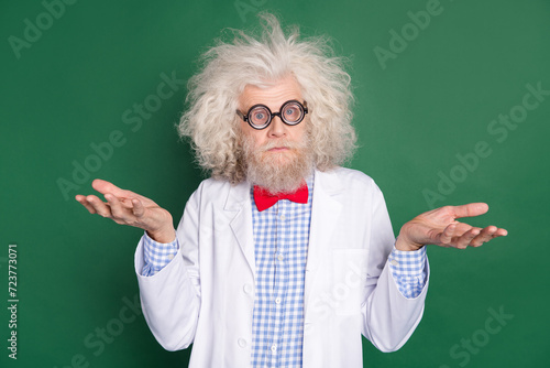 Photo of funky funny crazy scientist in glasses messy hair shrug shoulders doubtful isolated on green color background photo