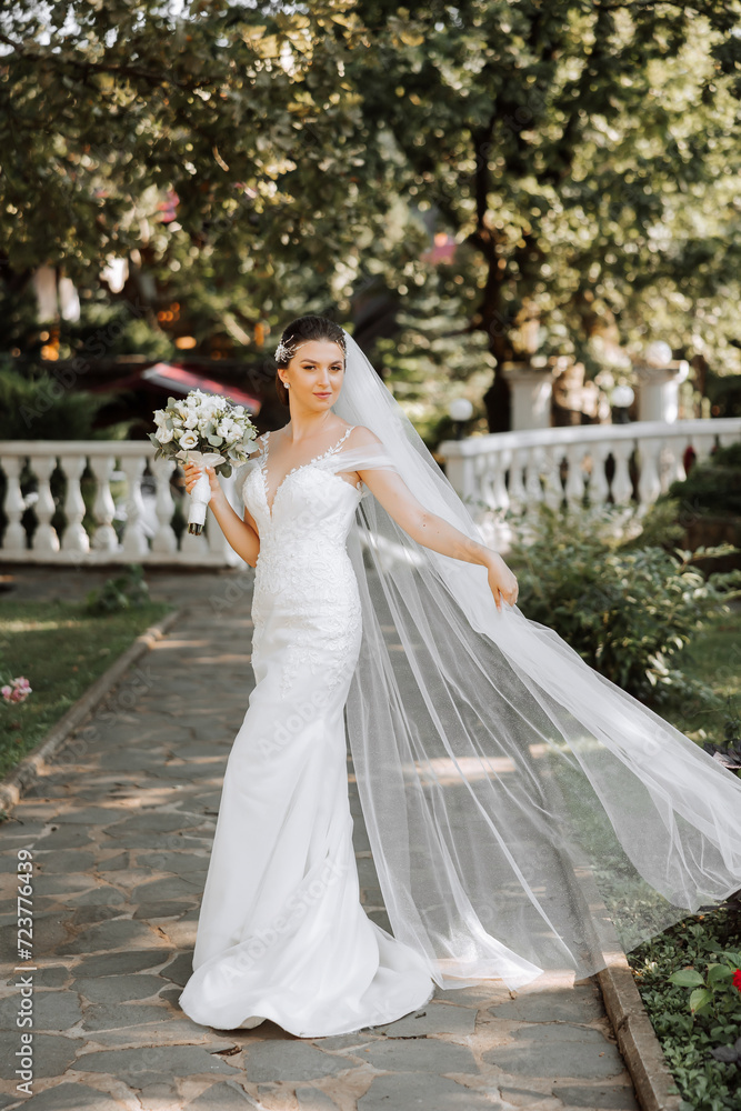 portrait of a beautiful young bride in a white dress with a long veil and a gorgeous hairstyle. Smiling bride. Wedding day. Gorgeous bride. Marriage.