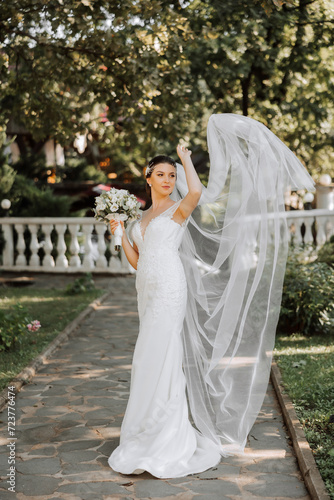 portrait of a beautiful young bride in a white dress with a long veil and a gorgeous hairstyle. Smiling bride. Wedding day. Gorgeous bride. Marriage.
