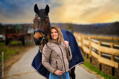 Woman with horse in portraits on a path with dramatic sky in the background.