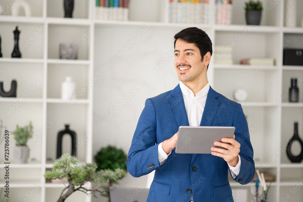 The businessman's engaging smile while using his tablet in the office conveys a sense of approachability and connectivity, crucial in the digitalized business world The businessman's engaging smile while using his tablet in the office conveys a sense of approachability and connectivity, crucial in the digitalized business world