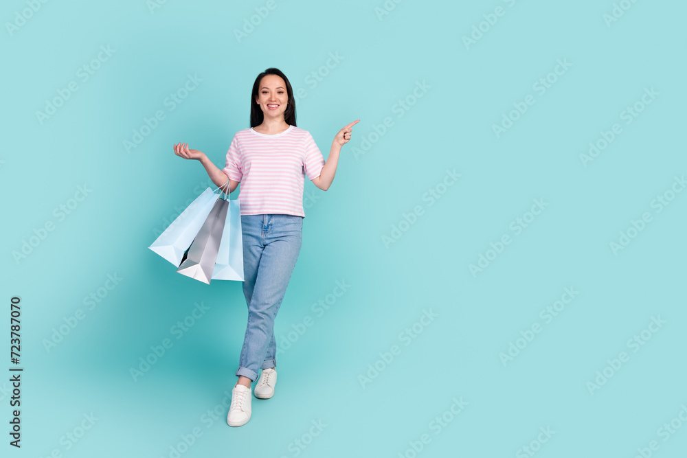 Full length photo of sweet shiny metis mixed race woman wear pink t-shirt rising bargains empty space isolated turquoise color background Full length photo of sweet shiny metis mixed race woman wear pink t-shirt rising bargains empty space isolated turquoise color background