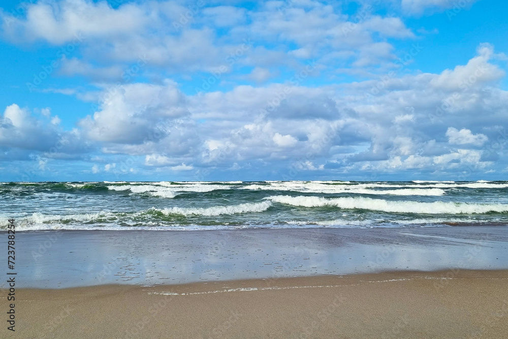 The waves of the sea or ocean roll over the sandy coast.